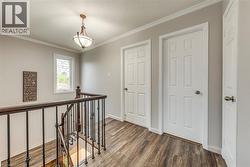 Upper landing featuring wood-finish flooring, light gray wall paint, and white trim molding - 