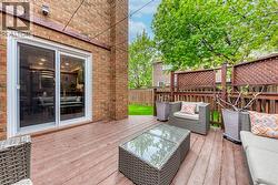 Spacious outdoor deck featuring rich wood-finish flooring, a full brick exterior, and a sliding glass door - 