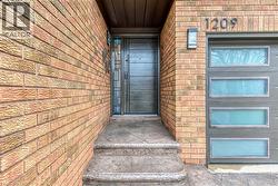 Brick exterior featuring a modern entry door with sidelight, exterior wall sconce lighting, and a contemporary garage door with frosted glass panels - 