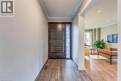 Foyer entryway featuring wood-look tile flooring and a dark wood entry door with a sidelight - 