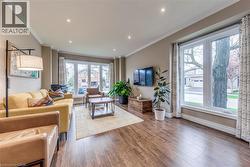 Living area featuring wood-finish flooring, recessed lighting, crown molding, and large bay windows - 