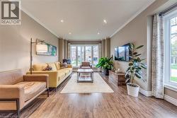 Spacious living area featuring wood-finish flooring, recessed lighting, and crown molding - 