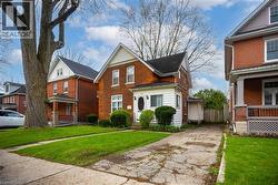 Brick residence featuring a white-sided front addition, gabled rooflines, and a paved driveway - 