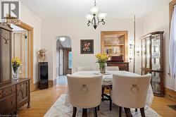 Dining area featuring wood-finish flooring, a classic chandelier, and an arched doorway - 