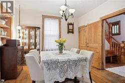 Dining area featuring wood-finish flooring, a chandelier, and natural wood trim around the window and doorways - 