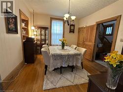 Warm dining area featuring natural wood-finish flooring, a decorative chandelier, and a built-in display cabinet - 