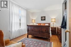Hardwood flooring throughout featuring a window with sheer curtains, textured wall finishes, and a built-in closet with an interior light - 