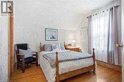 Bedroom featuring wood-finish flooring, a window with curtains, and a wood door frame - 