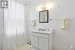 walls virtual painted in white -Bathroom vanity with an integrated sink and base cabinetry, complemented by a framed mirror and wall-mounted lighting - 