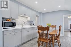virtual design contemporary kitchen featuring light gray cabinetry, a patterned tile backsplash, light-colored countertops, an undermount sink with a gooseneck faucet, and recessed lighting - 