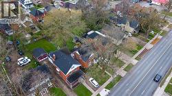 Residential property featuring a red brick exterior, a dark shingle roof, and a covered front porch - 