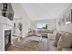 Bright and inviting living room with soaring ceilings, a cozy gas fireplace, and seamless flow to the kitchen and dining areas. - 