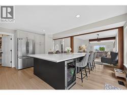 Massive waterfall island with bar seating, built-in wine fridge, quartz countertops, and plenty of prep space make this kitchen the heart of the home. - 