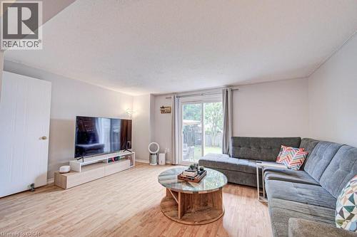 Living area featuring wood-finish flooring, light-toned walls, and a sliding glass door leading to the backyard - 854 Elgin Street N, Cambridge, ON 