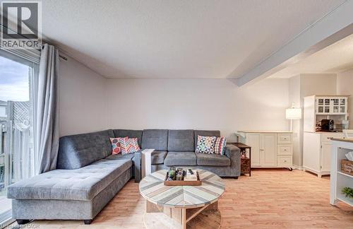 Spacious living area featuring wood-finish flooring, light-toned walls, and a sliding glass door providing exterior access - 854 Elgin Street N, Cambridge, ON 