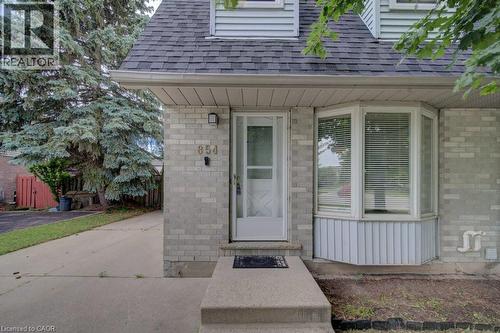 Front exterior featuring light-colored brick siding and a contrasting dark shingle roof - 854 Elgin Street N, Cambridge, ON 