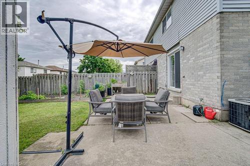Concrete patio area with a privacy fence, an exterior brick and siding facade, and a sliding glass door - 854 Elgin Street N, Cambridge, ON 