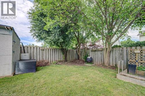 Grassed backyard featuring mature trees, a privacy fence, an exterior shed, and a raised garden bed - 854 Elgin Street N, Cambridge, ON 
