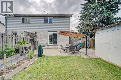 Expansive backyard featuring a concrete patio, sliding glass door access to the interior, a detached storage shed, a wood fence perimeter, and a raised garden bed - 854 Elgin Street N, Cambridge, ON 