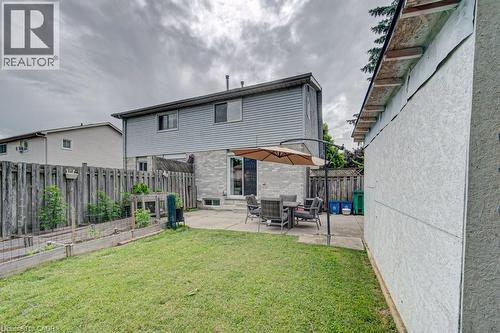 Spacious backyard featuring a manicured lawn, a large concrete patio, and built-in raised garden beds - 854 Elgin Street N, Cambridge, ON 