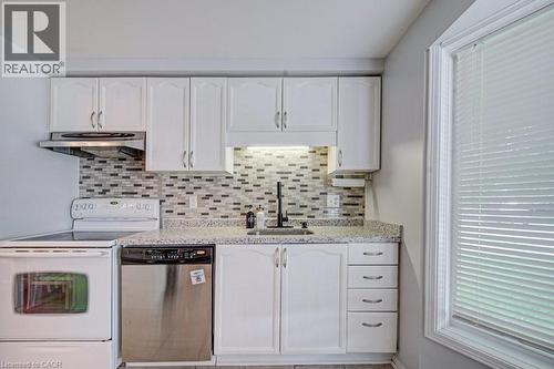 Kitchen featuring white cabinetry, a mosaic tile backsplash, and light-toned countertops - 854 Elgin Street N, Cambridge, ON 