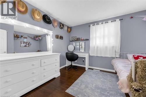 Bedroom featuring wood-finish flooring, light gray wall color, and a window with white drapery - 338 East 24Th Street, Hamilton, ON 