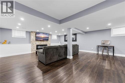 Spacious lower-level entertainment area featuring wood-finish flooring, a stone-clad fireplace, and recessed lighting - 338 East 24Th Street, Hamilton, ON 