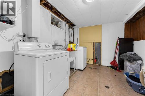 Laundry area with tile flooring, white paneled walls, and exposed ceiling joists - 338 East 24Th Street, Hamilton, ON 