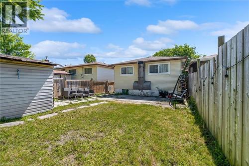 Rear exterior featuring a grass lawn, a wood fence, and a detached shed with horizontal siding - 338 East 24Th Street, Hamilton, ON 
