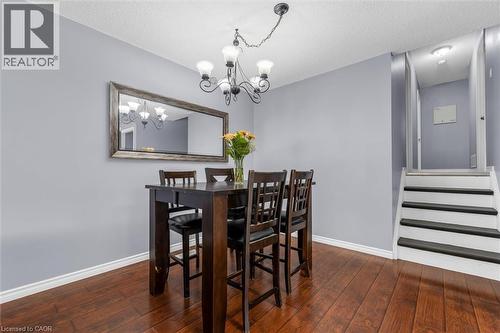Dining area featuring wood-finish flooring, a contemporary chandelier, and a decorative framed mirror - 338 East 24Th Street, Hamilton, ON 