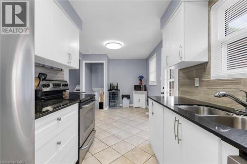 Contemporary kitchen featuring white cabinetry, dark countertops, a stainless steel range, and tile flooring - 338 East 24Th Street, Hamilton, ON 