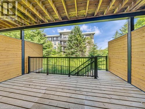 Spacious outdoor deck featuring wood-finish flooring, black metal railings, and natural wood privacy screens - 60 Arkell Road Unit# 51, Guelph, ON 