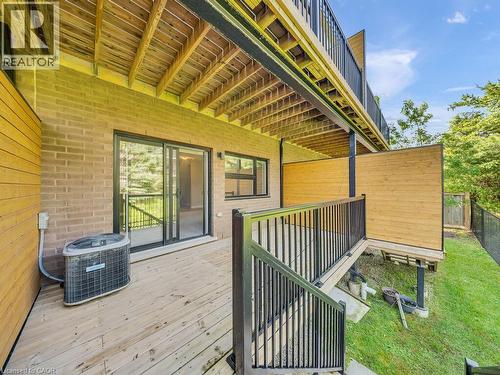 Wood-finish deck with black metal railings, featuring a sliding glass door entry - 60 Arkell Road Unit# 51, Guelph, ON 