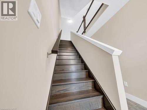 Contemporary staircase featuring dark wood-finish treads, a contrasting white balustrade, and a dark wood handrail with metallic supports - 60 Arkell Road Unit# 51, Guelph, ON 