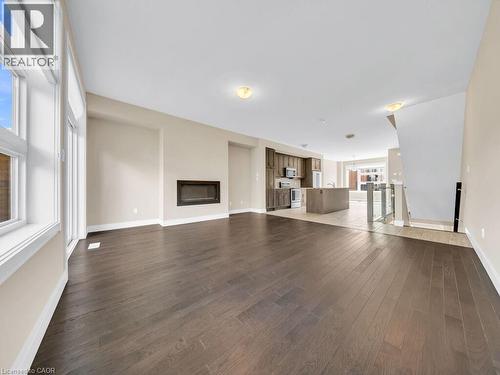 Spacious open-concept living area featuring dark wood-finish flooring, a modern linear fireplace, and large windows - 60 Arkell Road Unit# 51, Guelph, ON 