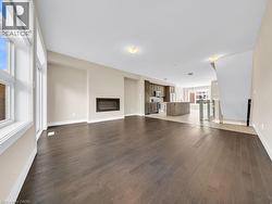 Spacious open-concept living area featuring dark wood-finish flooring, a modern linear fireplace, and large windows - 