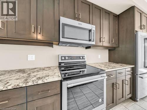 Kitchen featuring dark wood-finish cabinetry, light-toned countertops, and stainless steel appliances - 60 Arkell Road Unit# 51, Guelph, ON 
