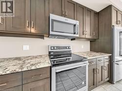 Kitchen featuring dark wood-finish cabinetry, light-toned countertops, and stainless steel appliances - 