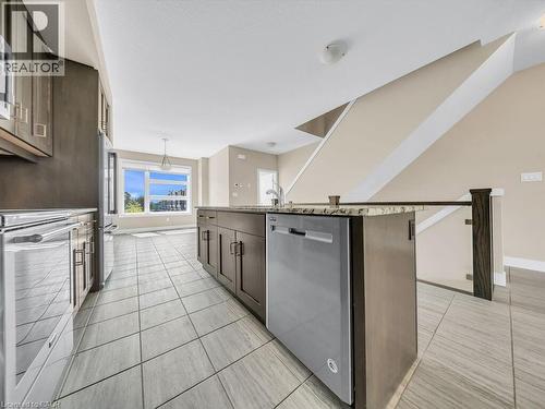 Kitchen island featuring a stainless steel dishwasher, granite-patterned countertop, and dark wood-finish cabinetry - 60 Arkell Road Unit# 51, Guelph, ON 