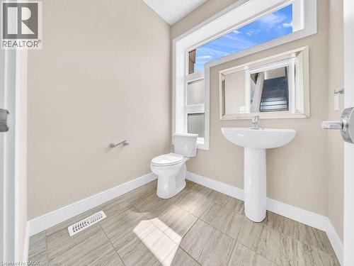 Bathroom featuring a pedestal sink, white toilet, and a large window with frosted lower panes - 60 Arkell Road Unit# 51, Guelph, ON 