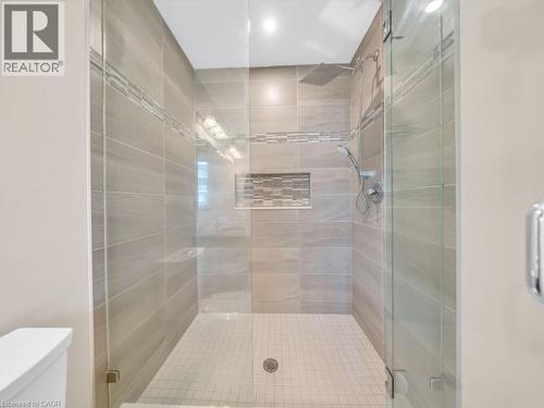 Frameless glass shower enclosure featuring large format wall tiles, a decorative mosaic accent band, a built-in shower niche, and a rainfall showerhead with a handheld spray - 60 Arkell Road Unit# 51, Guelph, ON 