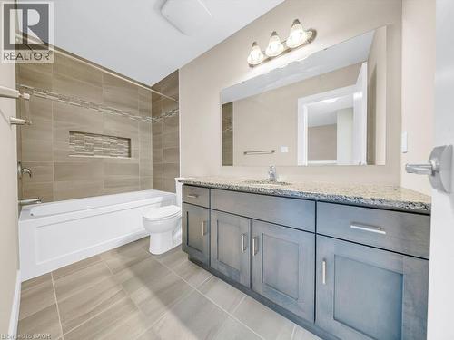 Modern bathroom featuring a single vanity with dark gray cabinetry, light speckled countertop, and chrome fixtures - 60 Arkell Road Unit# 51, Guelph, ON 