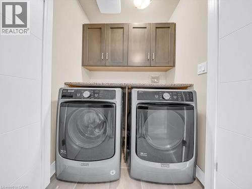 Dedicated laundry area featuring overhead cabinetry, a stone-finish countertop, and light-toned flooring - 60 Arkell Road Unit# 51, Guelph, ON 