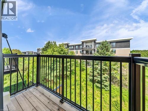 Private balcony with wood-finish flooring and black metal railings - 60 Arkell Road Unit# 51, Guelph, ON 