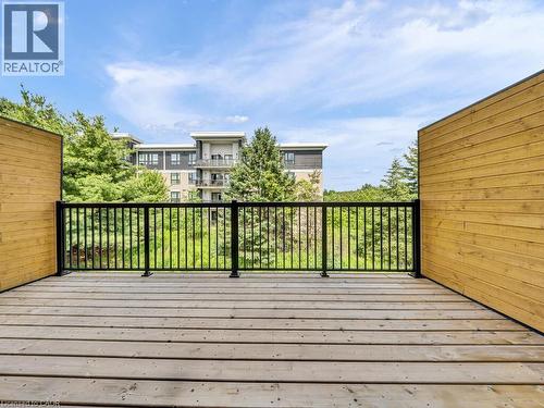 Expansive outdoor deck featuring wood plank flooring, black metal railings, and natural wood privacy walls - 60 Arkell Road Unit# 51, Guelph, ON 