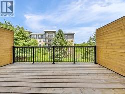 Expansive outdoor deck featuring wood plank flooring, black metal railings, and natural wood privacy walls - 