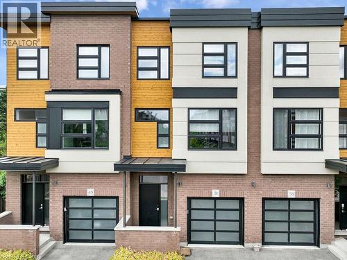 Modern townhome facade featuring a brick base, wood-panel siding, and contemporary window designs - 60 Arkell Road Unit# 51, Guelph, ON 