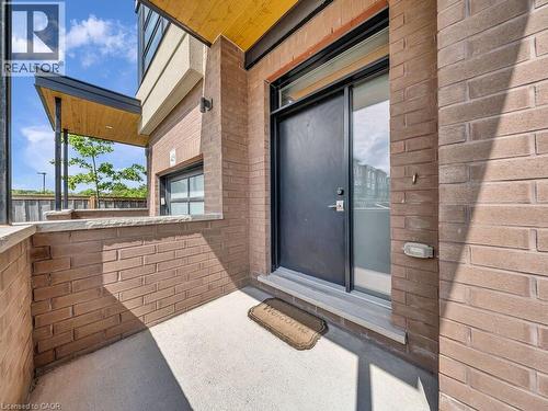 Front entry featuring a solid door with a side light, concrete patio, brick exterior, and a wood-finish soffit - 60 Arkell Road Unit# 51, Guelph, ON 