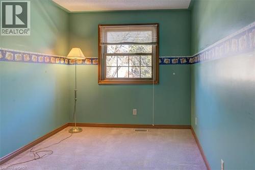 Upper North-West Bedroom 3: Another tranquil space with carpeted floors and classic wood trim, offering a restful retreat for the night. - 42 Donly Drive S Unit# 2, Simcoe, ON 
