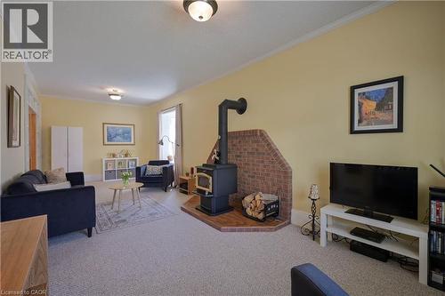 Room featuring a freestanding wood-burning stove with a brick hearth, wall-to-wall carpeting, and light yellow wall finishes - 25 Ahrens Street W, Kitchener, ON - Indoor Photo Showing Other Room